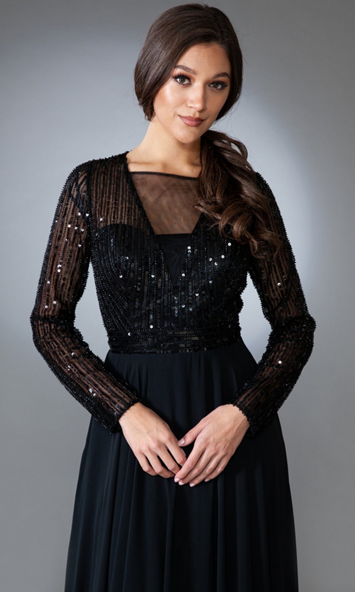 Model in the Long-Sleeve Long Modest Prom Dress 7036 with sheer, sequined sleeves and a partially sheer neckline, posed against a neutral gray background.